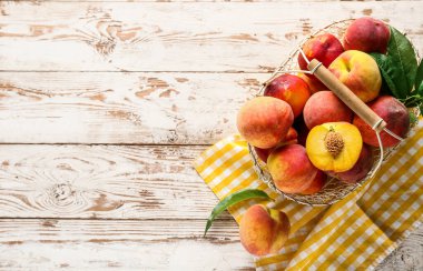 Hafif ahşap arka planda bir sepet taze şeftali.