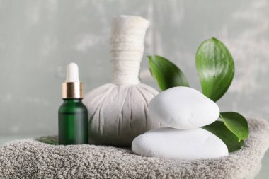 Kaplıca taşları, yeşil yapraklar, bitkisel poşet ve yeşil grunge arka planda bir şişe kozmetik ürünü, yakın plan