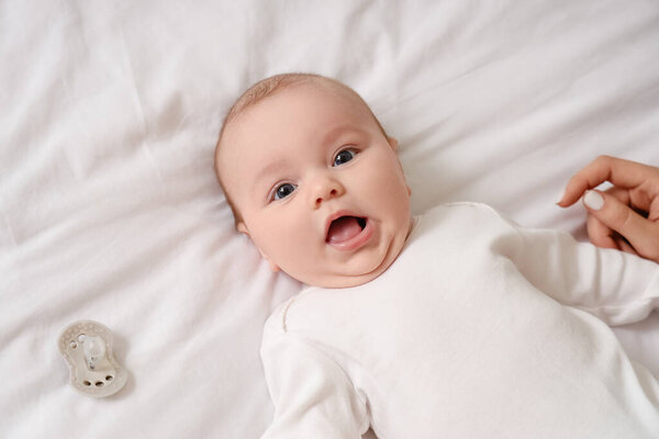 Cute baby lying on bed, top view