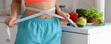 Mutfakta belini ölçen genç bir kadın. Diyet kavramı