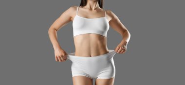 Gri arka planda beyaz iç çamaşırlı güzel bir kadın.