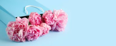 Açık mavi arka planda güzel pembe şakayıklı alışveriş torbası metin için yer var, yakın plan.