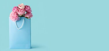 Açık mavi arka planda güzel pembe şakayıklı alışveriş çantası ve metin için yer.