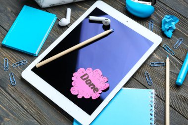 Kelime DONE ile yapışkan not, tablet bilgisayar ve kırtasiye koyu ahşap arka plan, yakın çekim