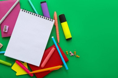 Boş defter ile kompozisyon ve yeşil arkaplan üzerinde farklı kırtasiye