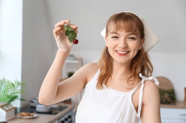 Mutfakta kiraz dalı olan mutlu, güzel genç bir kadın.