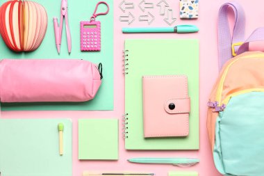 Renkli arka planda farklı kırtasiye malzemesi içeren şık bir okul çantası ve kalem çantası.