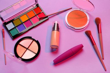 Güzel göz falı paletleri ve mor arka planda farklı dekoratif kozmetikler.