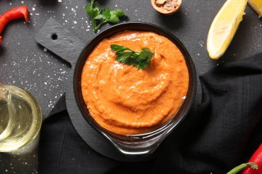 Siyah arka planda bir kase lezzetli muhammara.