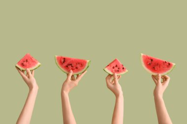 Yeşil arka planda olgun karpuz dilimleriyle kadın elleri.