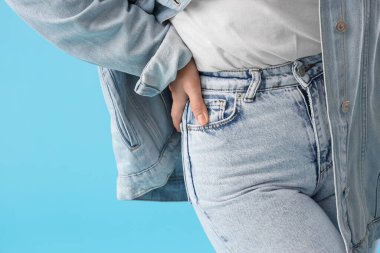 Mavi arka planda kot elbiseli şık genç bayan, yakın plan.