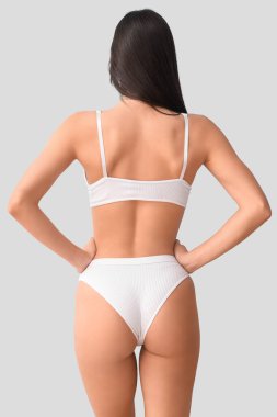 Mavi arka planda beyaz iç çamaşırlı genç bir kadın.