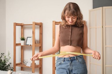 Evinde belini ölçen genç ve güzel bir kadın. Kilo verme konsepti