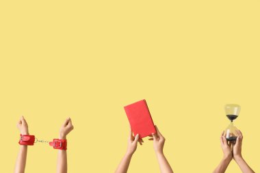 Kadın elleri kum saati, kelepçe ve sarı arka plan kitabı tutuyor.