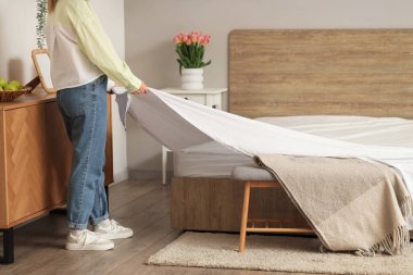 Modern yatak odasında yatak yapan kadın.