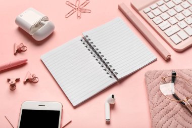 Pembe arka planda not defteri, ataç ve kulaklık ile kompozisyon