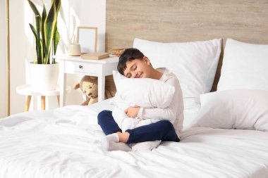 Yatak odasında oturan şirin, mutlu küçük çocuk.