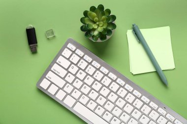 Flaş bellekli bilgisayar klavyesi, sulu ve yeşil arka planda kalemli kağıt. Üst görünüm