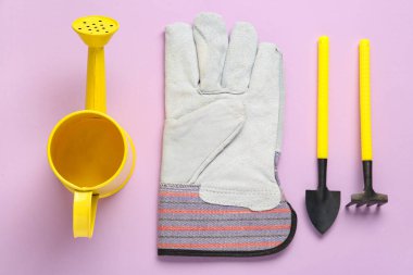 Leylak arka planında bahçe aletleri, eldiven ve sulama kutusu