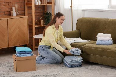 Genç bir kadın evde giysileri katlıyor.