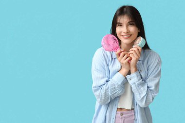 Mavi arka planda mini hayranları olan genç bir kadın.