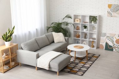 Gri kanepesi, raf ünitesi ve sehpası olan modern oturma odasının içinde.