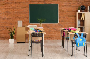 Kara tahta, masa ve sırt çantalı sınıfın içi.