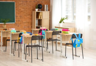 Kara tahta, masa ve sırt çantalı sınıfın içi.