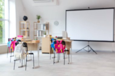 Projektör ekran ve masalarla ışık sınıfının bulanık görüntüsü