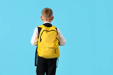 Mavi arka planda sırt çantası olan küçük bir çocuk.