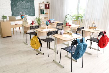 Sırt çantalı okul sıraları ve açık renkli sınıflarda kara tahta.