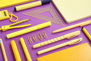 Mor arkaplanda farklı kırtasiye malzemesi, yakın plan