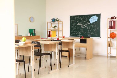 Kara tahtası, raf ünitesi ve masaları olan boş sınıfın içi