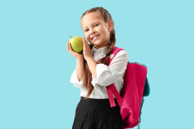 Mavi arka planda elma olan küçük okul kızı.