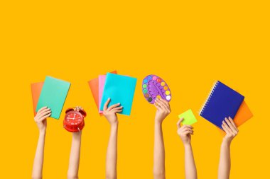 Palet, yapışkan notlar ve sarı arkaplan üzerine not defterleri olan birçok el