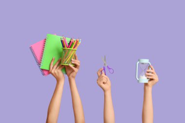 Mavi zemin üzerinde kırtasiye, makas ve not defterleri olan birçok el