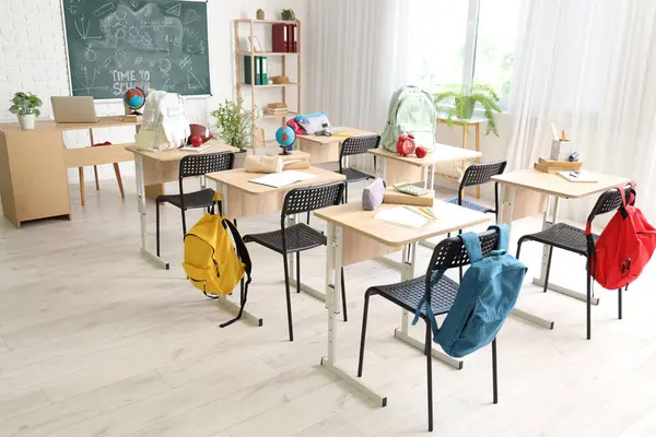 Sırt çantalı okul sıraları ve açık renkli sınıflarda kara tahta.