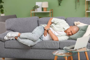 Apandisiti olan genç bir adam evdeki kanepede yatıyor.