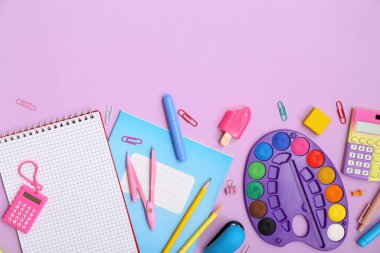 Leylak arka planında defter, palet ve hesap makinesi olan okul malzemeleri. Üst görünüm