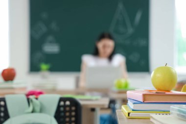 Sınıfta masa başında kitap olan elma, yakın plan.