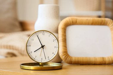 Odadaki sehpanın üzerinde vazo ve çerçeveli altın çalar saat. Yakın çekim.