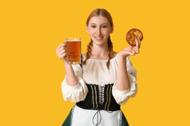 Güzel mutlu Ekim Festivali garsonu. Sarı arka planda bir kupa bira ve krakerle.