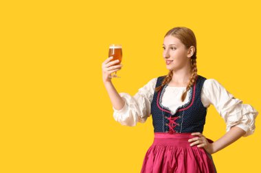 Güzel mutlu Ekim Festivali garsonu. Sarı arka planda bir bardak birayla.