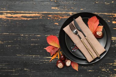 Kestaneli ve siyah ahşap arka planda sonbahar yapraklı güzel bir masa.