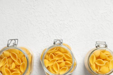 Beyaz arka planda çiğ koni makarnalı kavanozlar