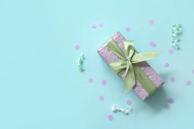 Leylak hediye kutusu, üzerinde yılan yağı ve mavi arka planda konfeti.