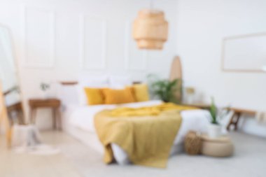 Büyük yatak ve bitkilerle aydınlık yatak odasının bulanık görüntüsü