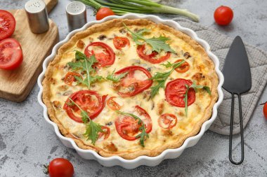 Arkaplanda yeşil soğan ve roka yapraklı lezzetli domates turtası, yakın plan.