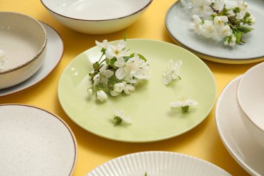 Sarı arka planda çiçek açan dalları olan farklı temiz tabakalar, yakın plan.