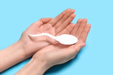 Mavi arka planda sperm hücresi olan eller